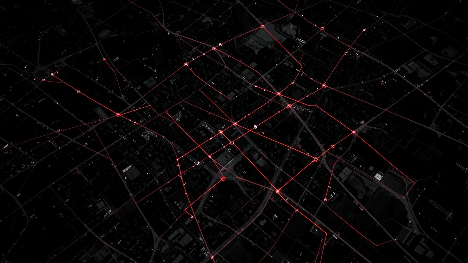 Dark aerial view of a city grid with glowing route lines